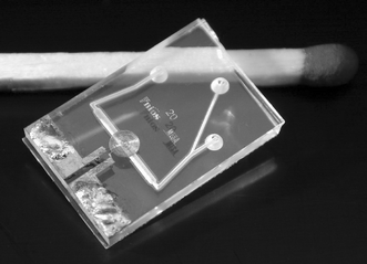 The glass NMR chip with planar micro coil. Chip size is 1 by 1.5 cm; channel width underneath coil is 500 µm.